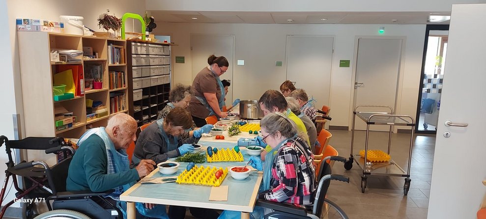 Bewohnerinnen und Bewohner färben mit ehrenamtlicher Mitarbeiterin Eier