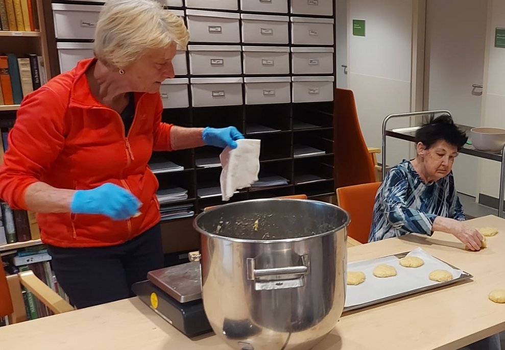 Bewohnerin und ehrenamtliche Mitarbeiterin backen Pinzen
