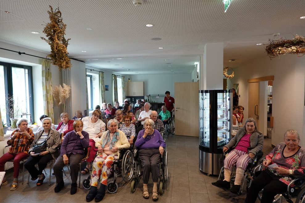 Bewohnerinnen und Bewohner sitzen im Raba Cafe zusammen und warten.