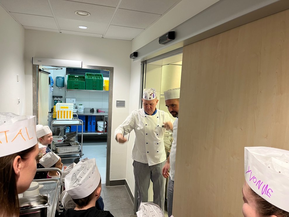 Küchenleiter begrüßt die Kinder des Kindergartens in der Küche