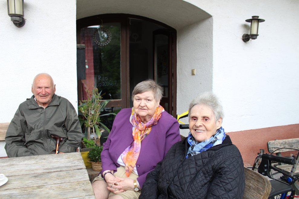 Bewohnerinnen und Bewohner sitzen gemeinsam am Tisch