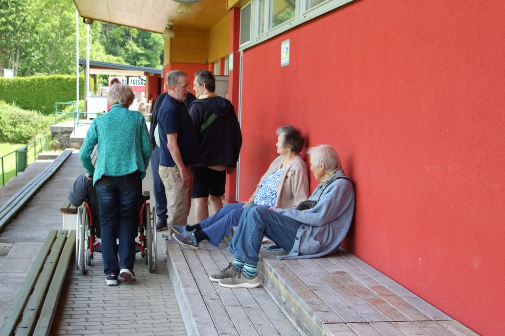 Bewohnerinnen und Bewohner machen eine kurze Pause auf der Tribüne und feuern an