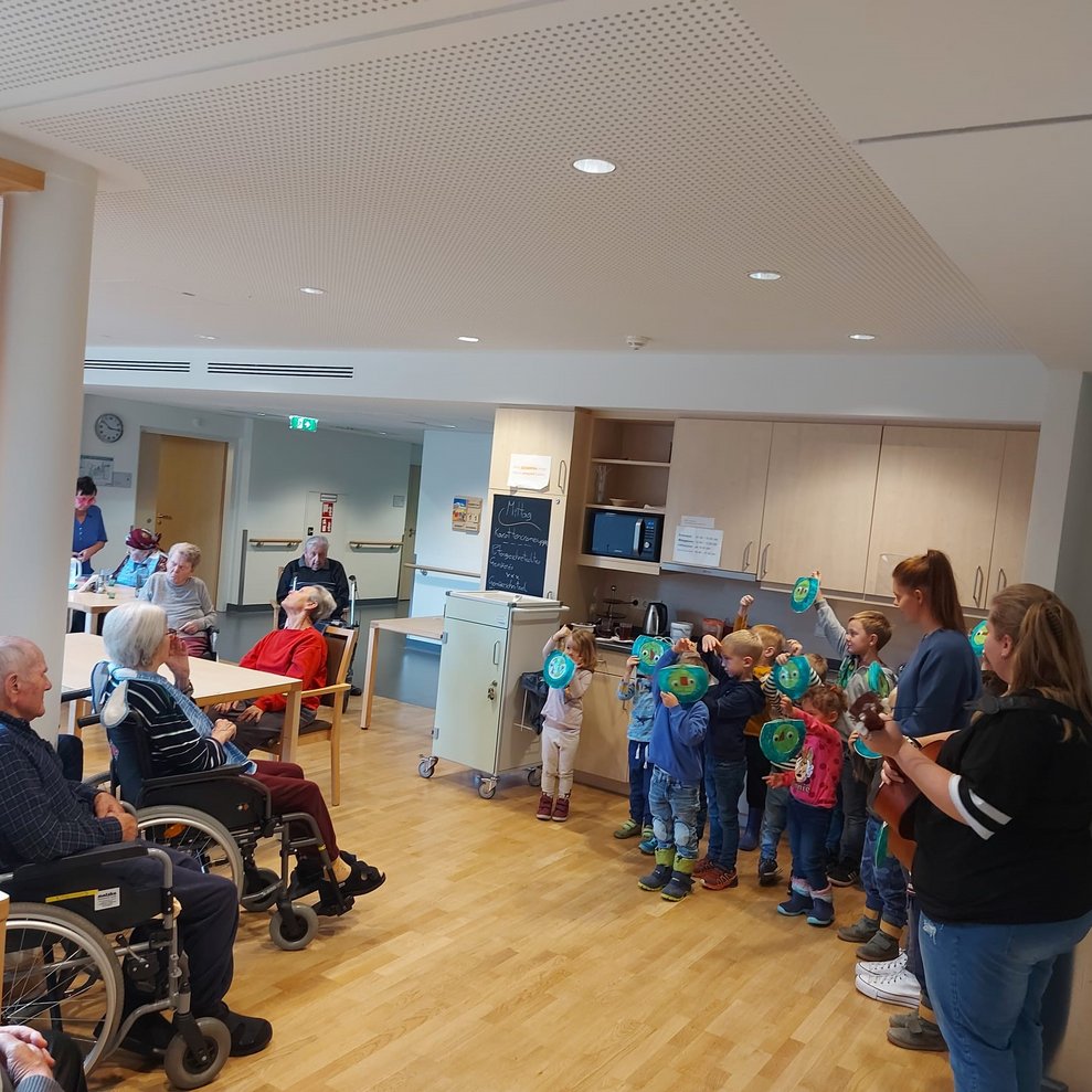 Bewohnerinnen und Bewohner hören den Kindern zu.