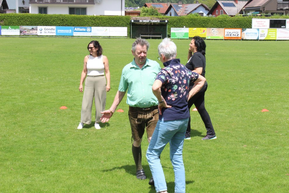 Bewohnerinnen und Bewohner spielen mit ehrenamtlichen Mitarbeiterinnen Fußball