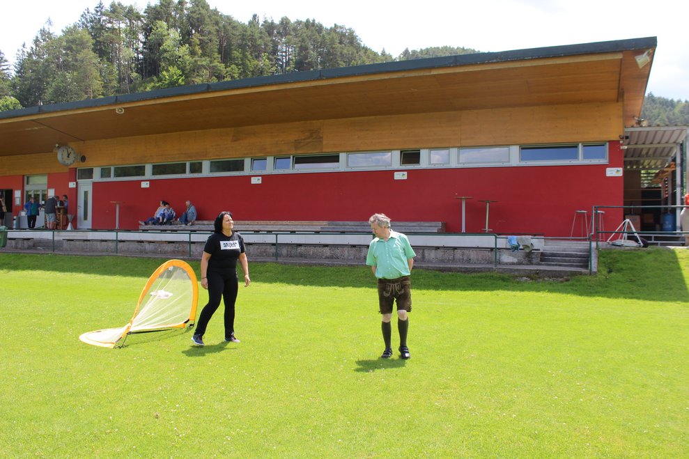 Bewohner und Mitarbeiterin spielen Fußball am Fußballplatz