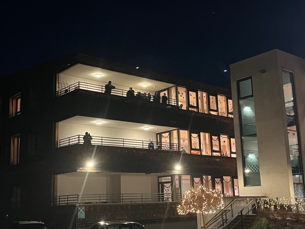 Bewohnerinnen und Bewohner beobachten vom Balkon aus das Spektakel