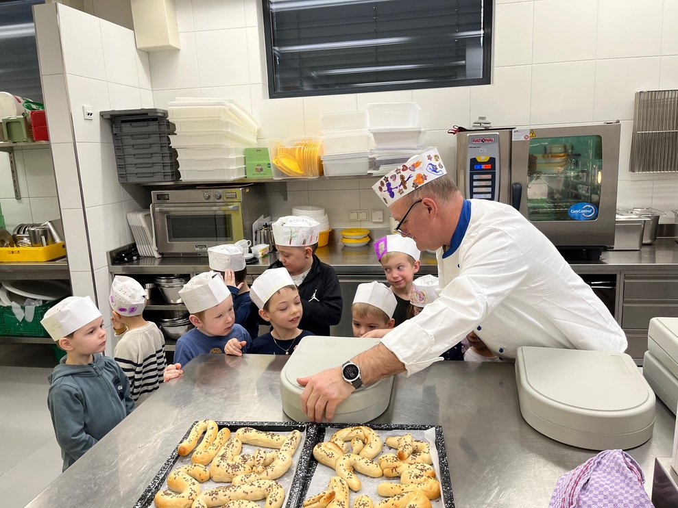 Küchenleiter Reinhard zeigt den Kindern wie er ihr Mittagessen verpackt.
